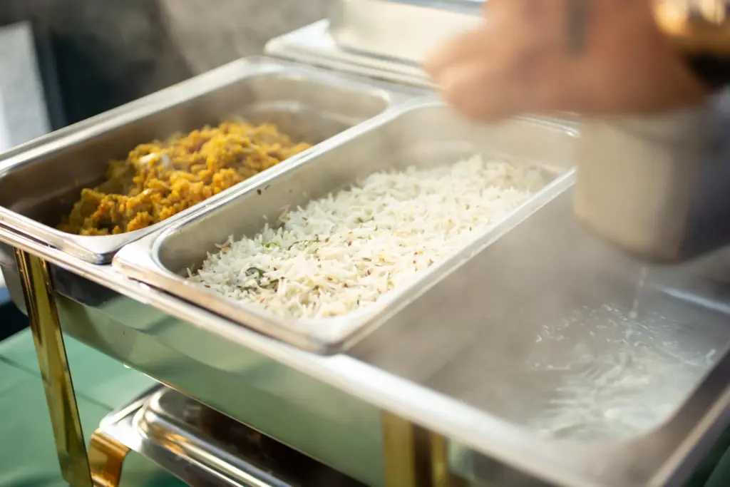Chafing dishes with steaming white rice and yellow curry meal
