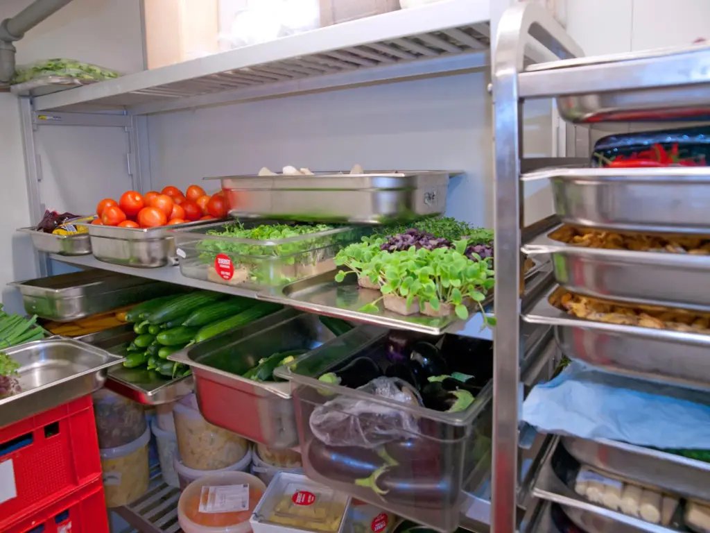 Commercial kitchen walk in cooler with metal shelves and produce