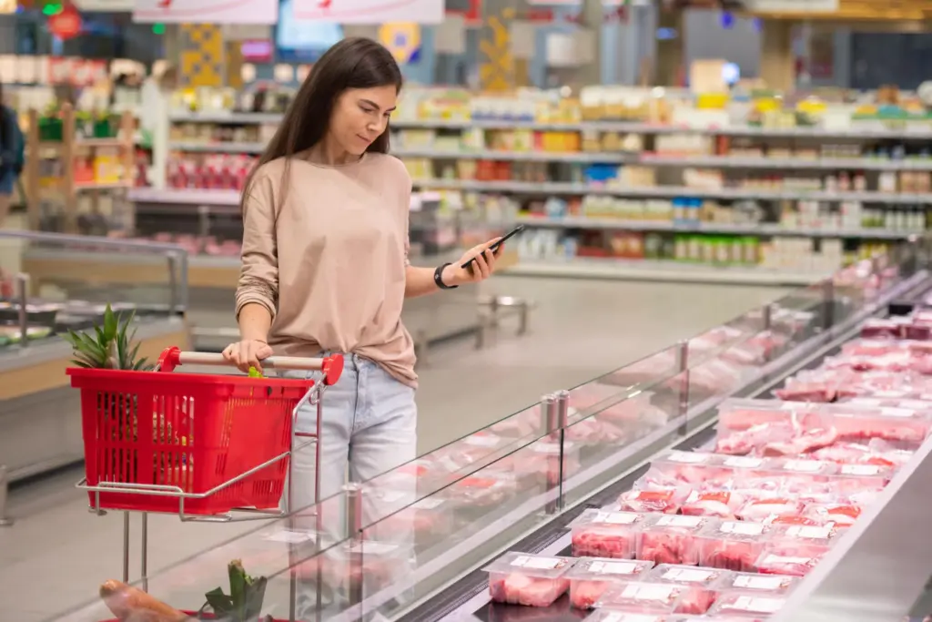 Woman shopping for meat in supermarket using smartphone app